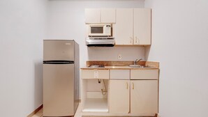 A compact kitchen with a refrigerator, microwave, and basic cabinetry.