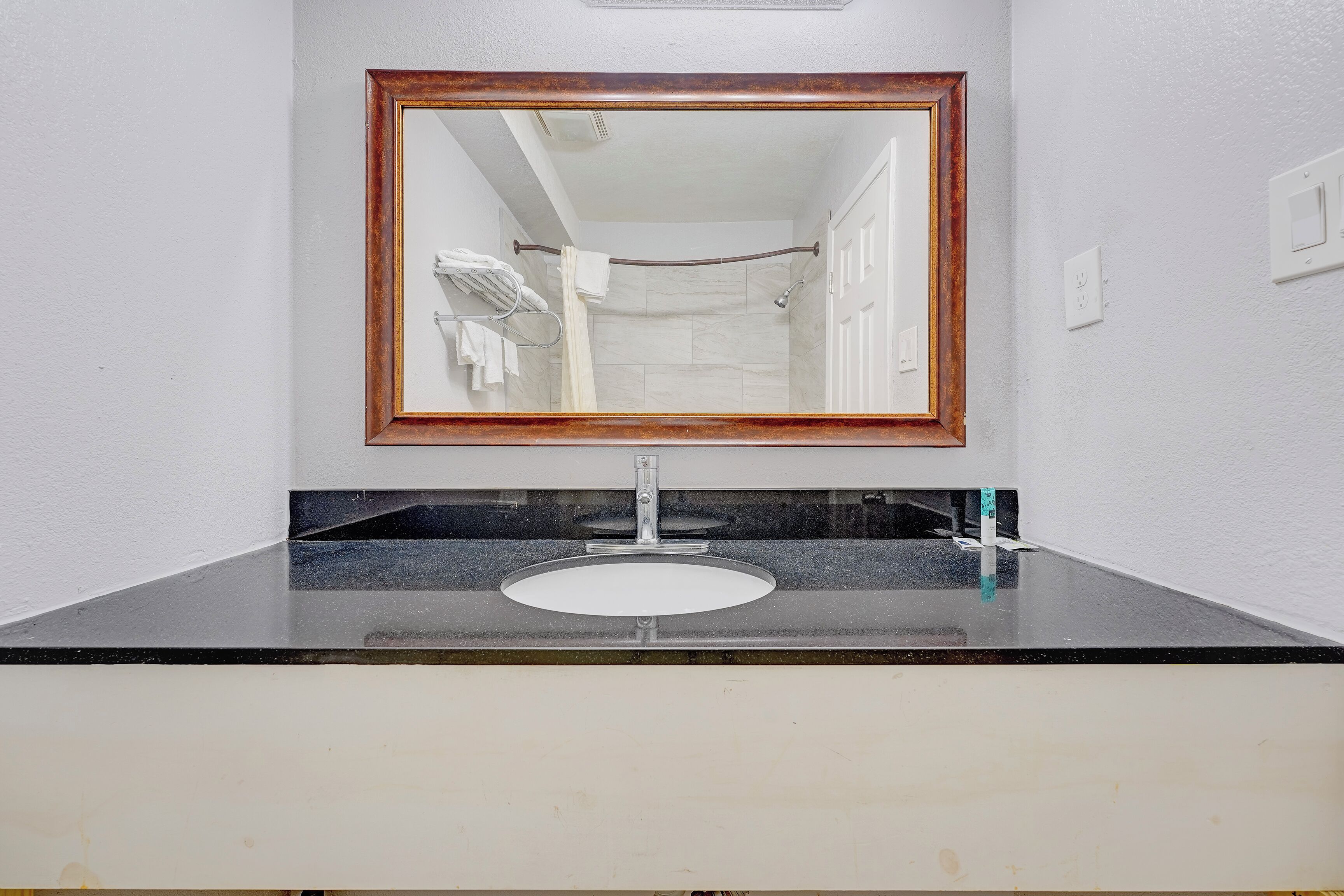 Une salle de bain avec un miroir, un lavabo et une douche.