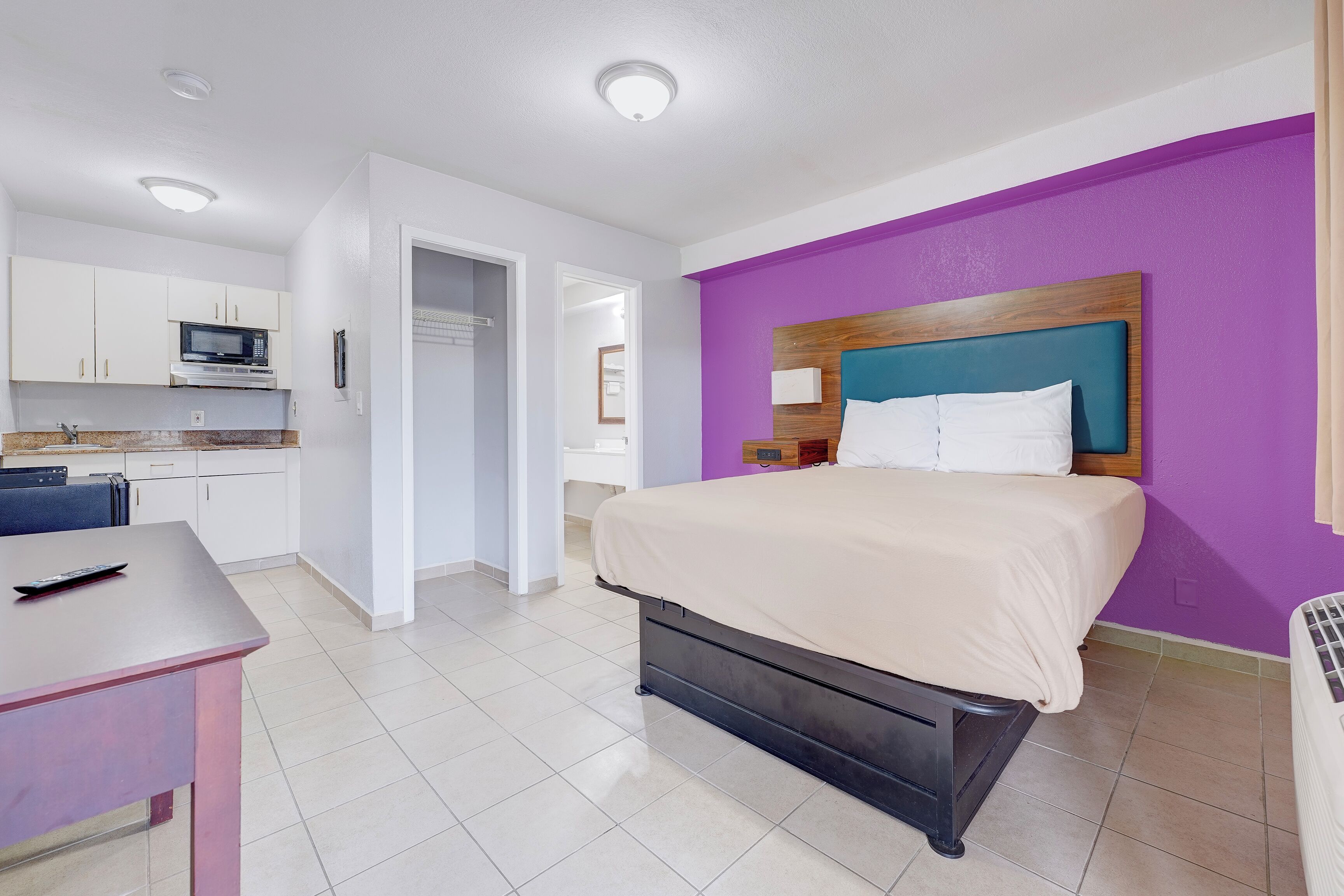 Une chambre d’hôtel comprenant un lit, un bureau, une kitchenette et une salle de bain.
