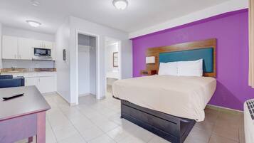 Une chambre d’hôtel comprenant un lit, un bureau, une kitchenette et une salle de bain.