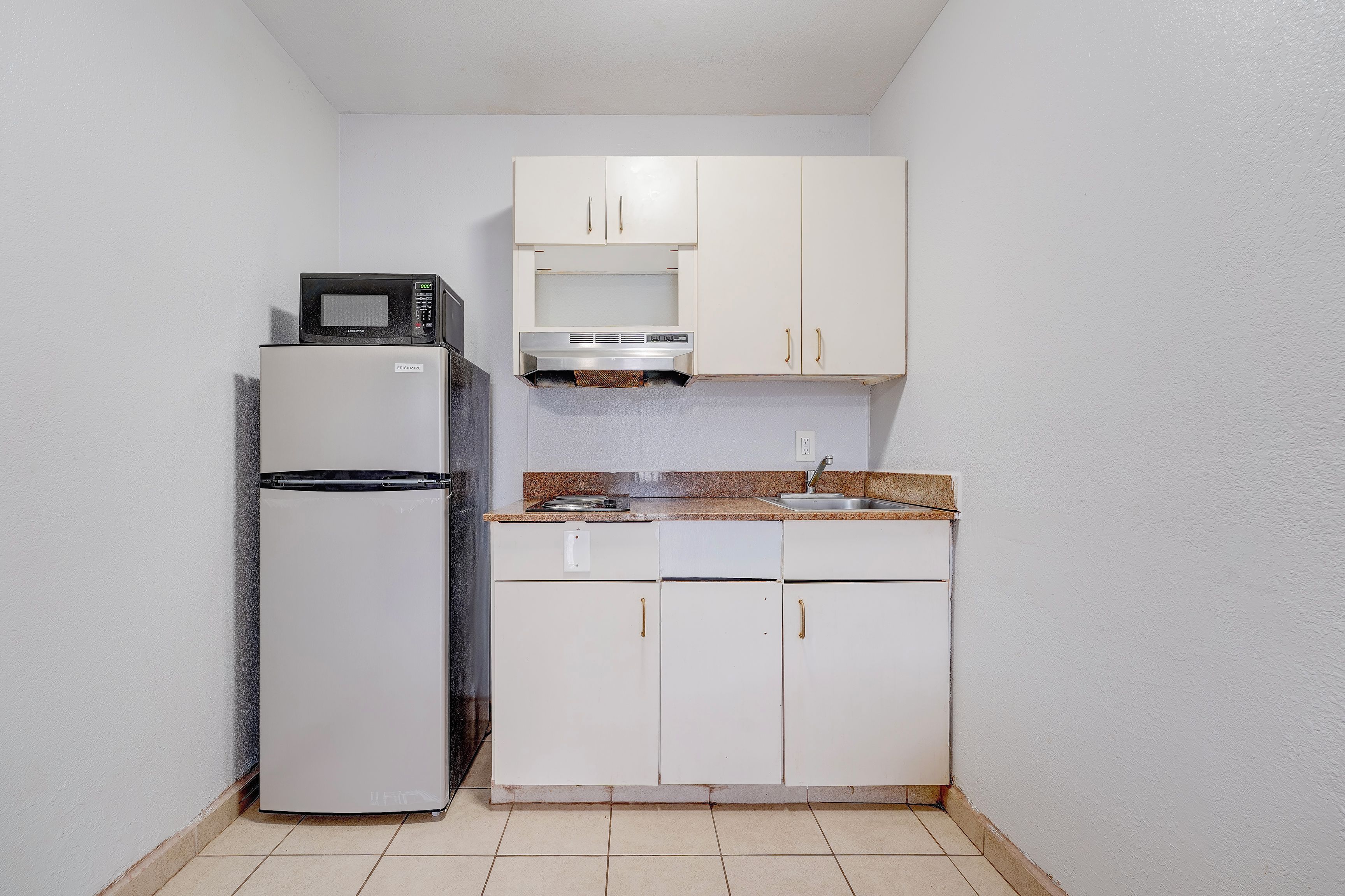 Una cocina compacta equipada con refrigerador, microondas y lavamanos.