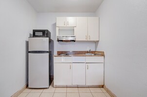 A compact kitchen with a refrigerator, microwave, and a sink.