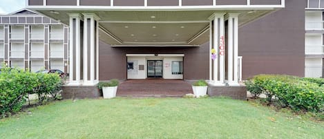 A multi-story building with a covered entrance, a brick facade, and a flat roof.