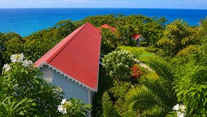 A coastal property with a red-roofed building, lush greenery, and a view of the ocean. - Mount Edgecombe Boutique Hotel (Victoria)