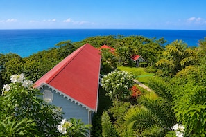 A coastal property with a red-roofed building, lush greenery, and a view of the ocean. - Mount Edgecombe Boutique Hotel (Victoria)