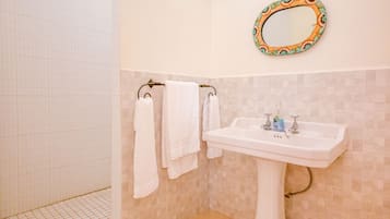 A bathroom with a white sink, a mirror with a decorative frame, and a towel rack with white towels.