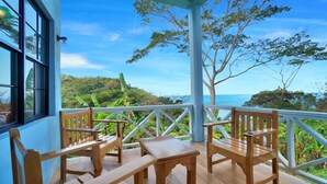 A wooden deck with a table and chairs, overlooking a lush landscape and the sea. - Mount Edgecombe Boutique Hotel (Victoria)