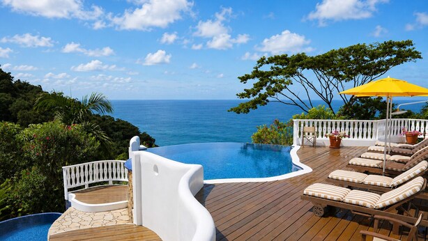 A wooden deck with a pool, lounge chairs, and a view of the ocean. - Mount Edgecombe Boutique Hotel (Victoria)