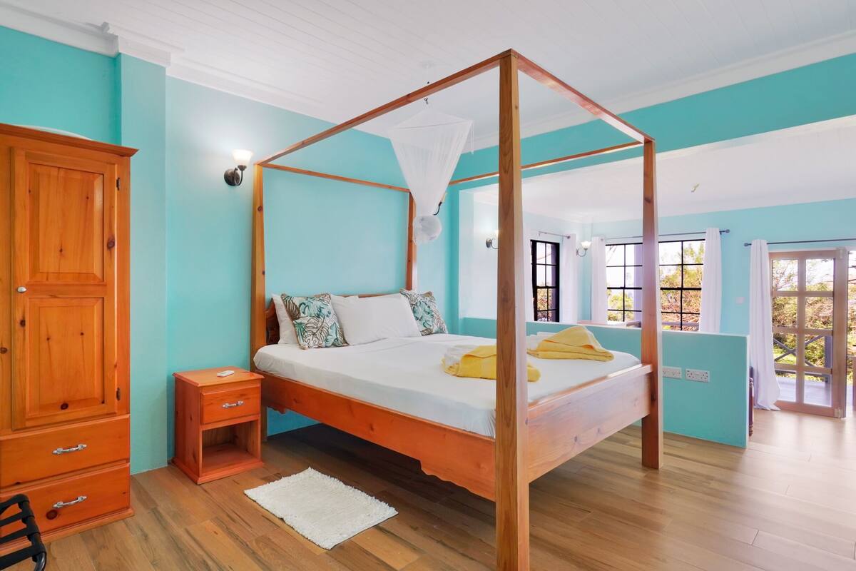 Quarto com uma cama de dossel, um guarda-roupa de madeira e uma pequena mesa de cabeceira.