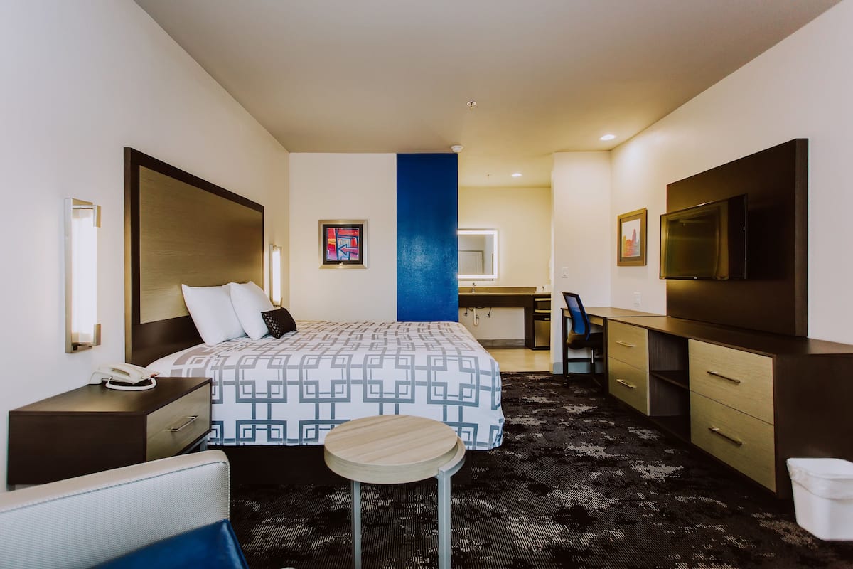 Ein Hotelzimmer mit Bett, Nachttisch, Schreibtisch, Stuhl und einem kleinen runden Tisch.