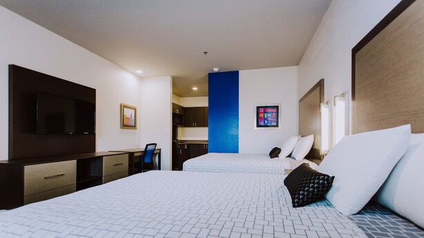 Une chambre d’hôtel avec deux lits, une télévision, un bureau et une kitchenette.