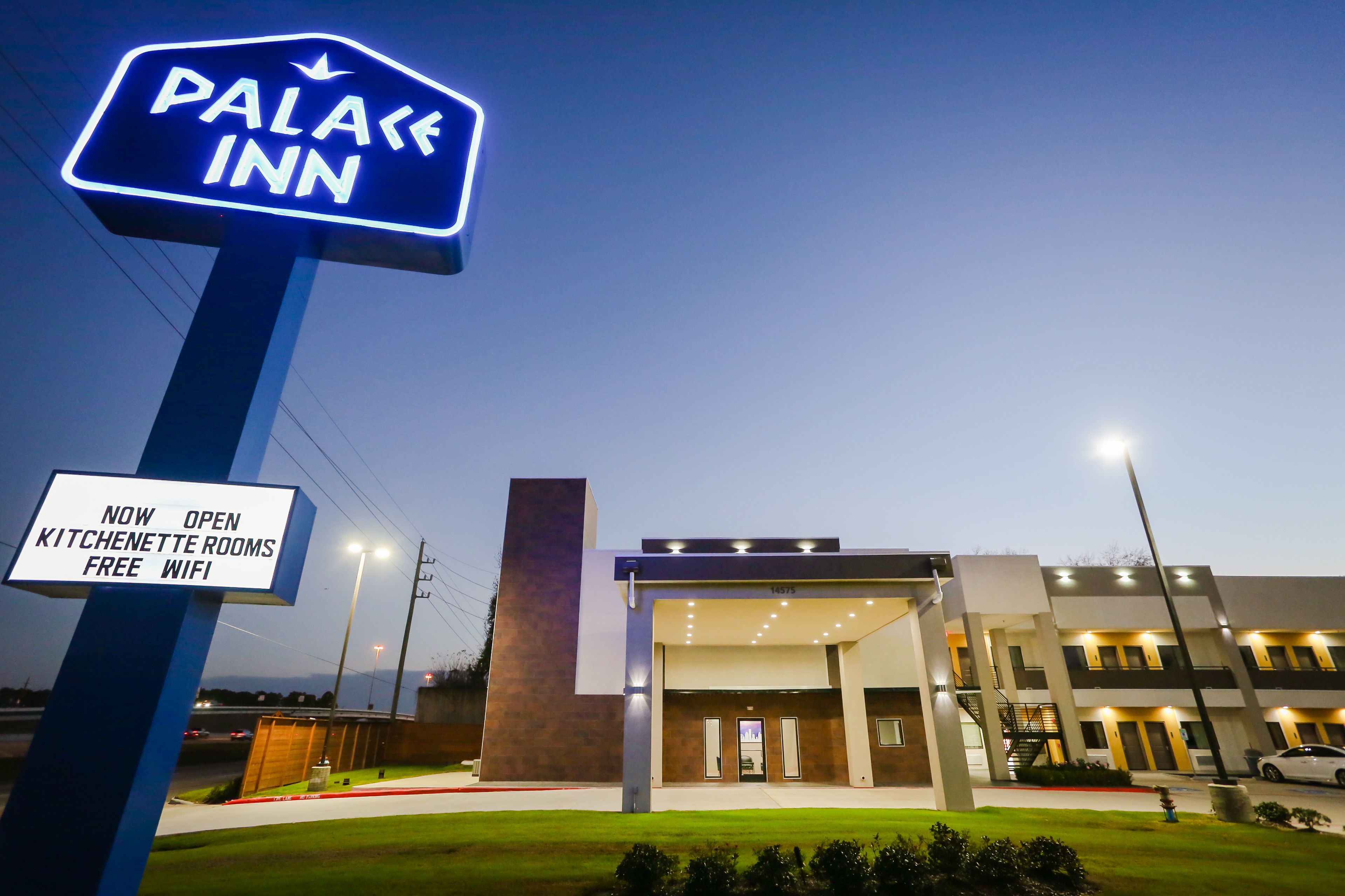 Un hotel llamado "Palace Inn" con un letrero que indica habitaciones con kitchenette y WiFi gratuito.