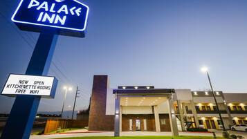Un hotel llamado "Palace Inn" con un letrero que indica habitaciones con kitchenette y WiFi gratuito.