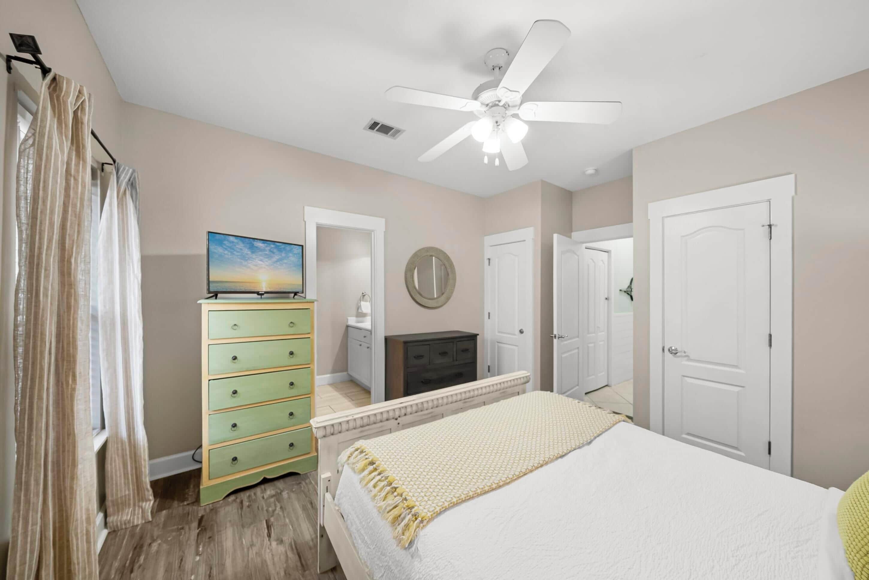Un dormitorio con cama, cómoda, ventilador de techo y espejo.