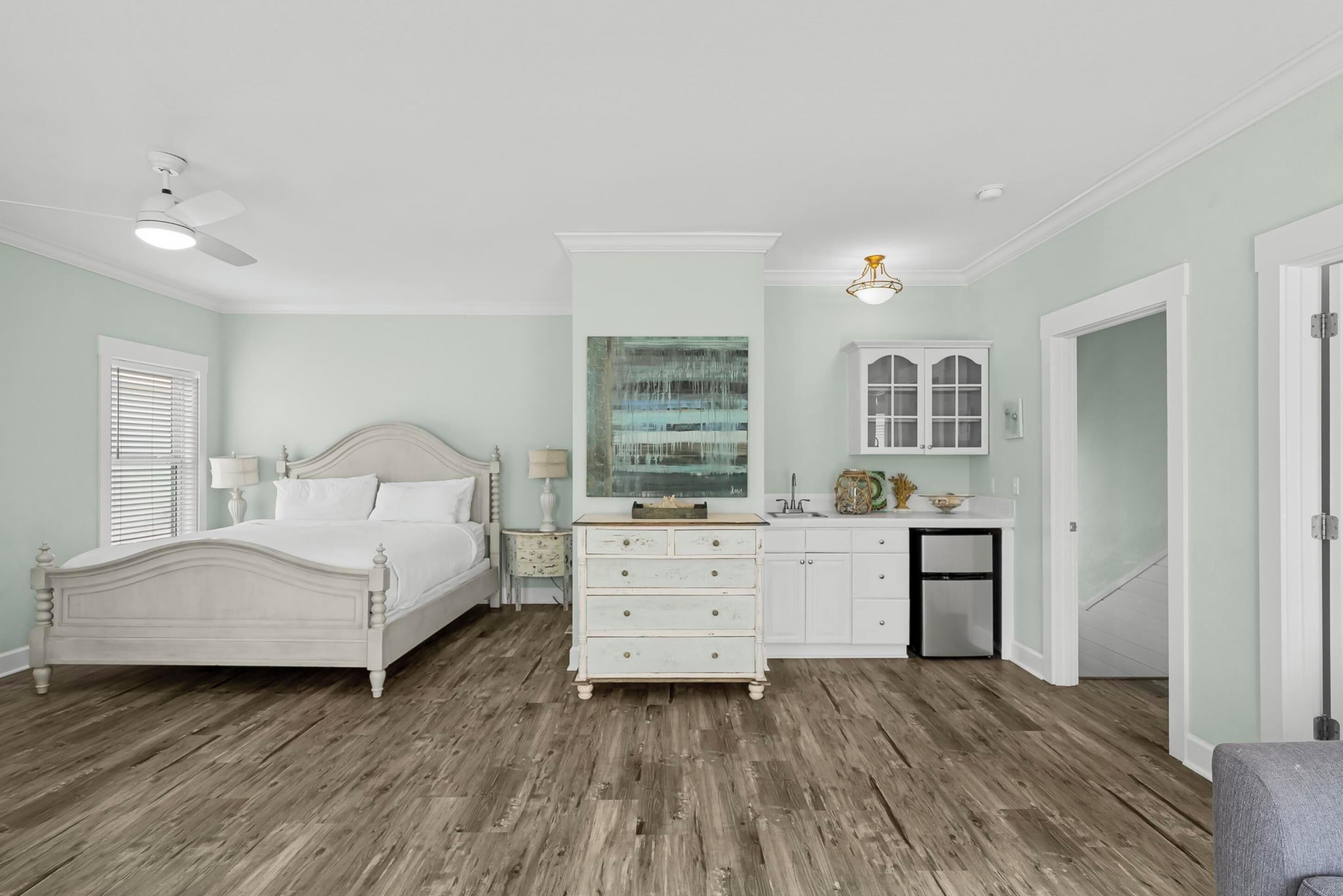 A bedroom with a bed, dresser, and artwork on the wall.