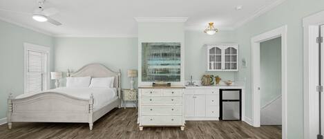 A bedroom with a bed, dresser, and artwork on the wall.