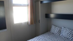 A bedroom with a bed, a window with curtains, and a wardrobe. - Torreira Camping & Bungalows (Murtosa)