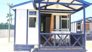 A small, single-story structure with a covered patio area, a door, and a window. - Torreira Camping & Bungalows (Murtosa)