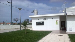 A modern building with a white exterior, a small tree in the front yard, and a paved walkway leading to the entrance. - Torreira Camping & Bungalows (Murtosa)
