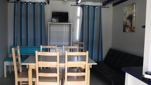 A dining area with a table and chairs, a bench, and a sofa. - Torreira Camping & Bungalows (Murtosa)