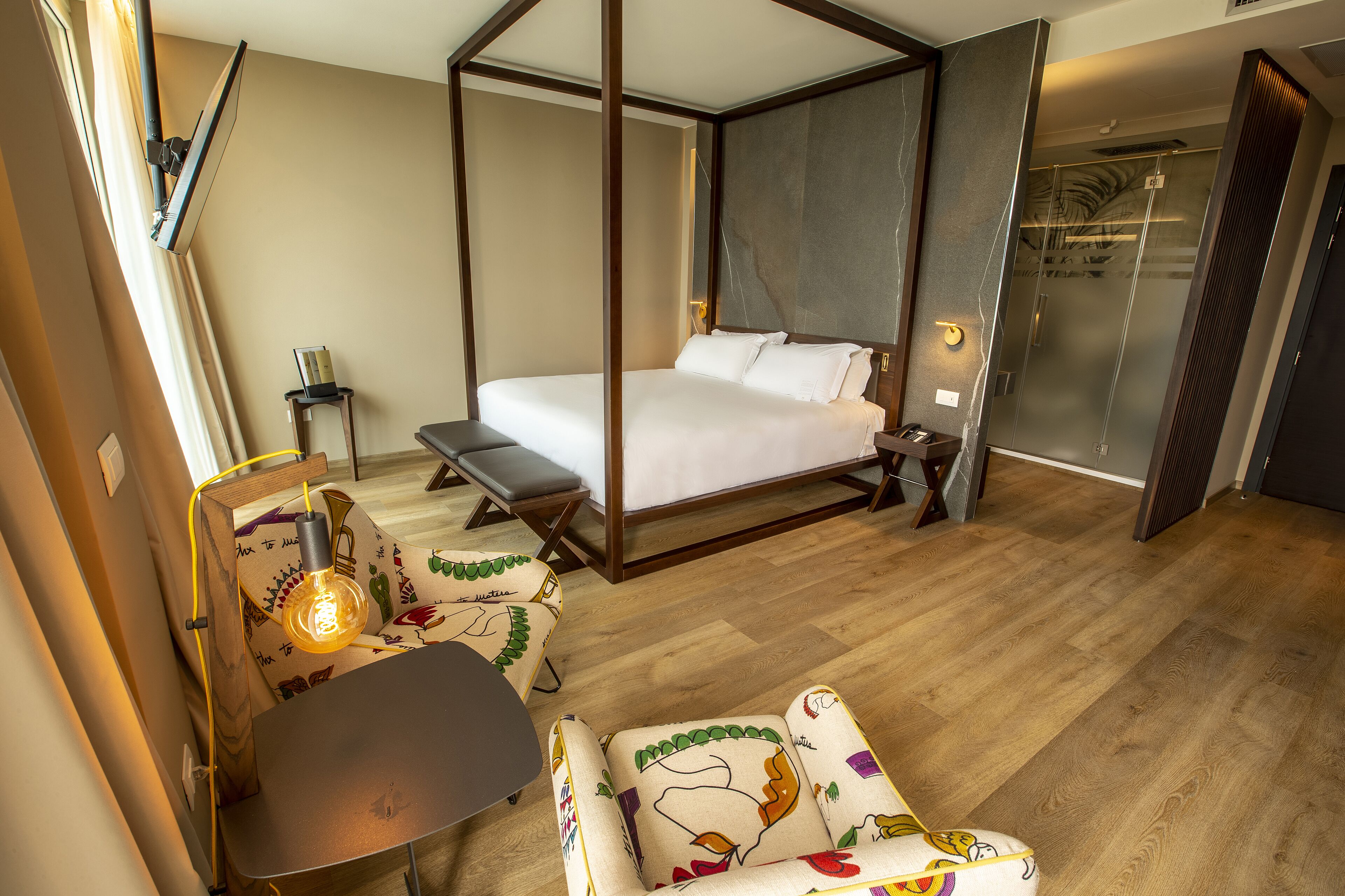 Un dormitorio moderno con cama con dosel, mesita de noche, una silla y un escritorio.