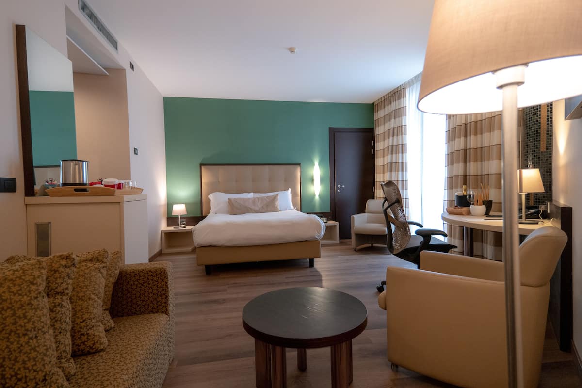 A hotel room with a bed, a sofa, a round table, and a chair.