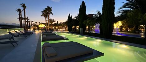 Un área junto a la piscina con sillones de descanso y una fuente de agua.