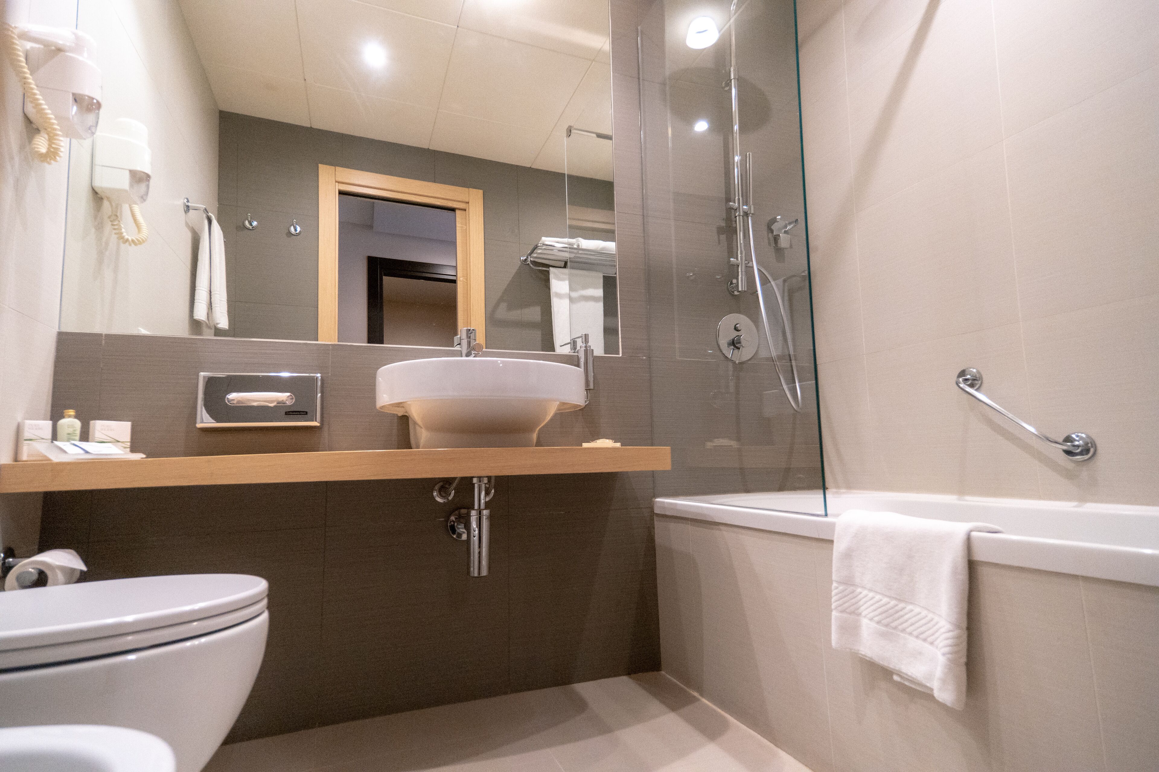 A modern bathroom with a glass-enclosed shower, a white sink, and a toilet.