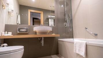 A modern bathroom with a glass-enclosed shower, a white sink, and a toilet.