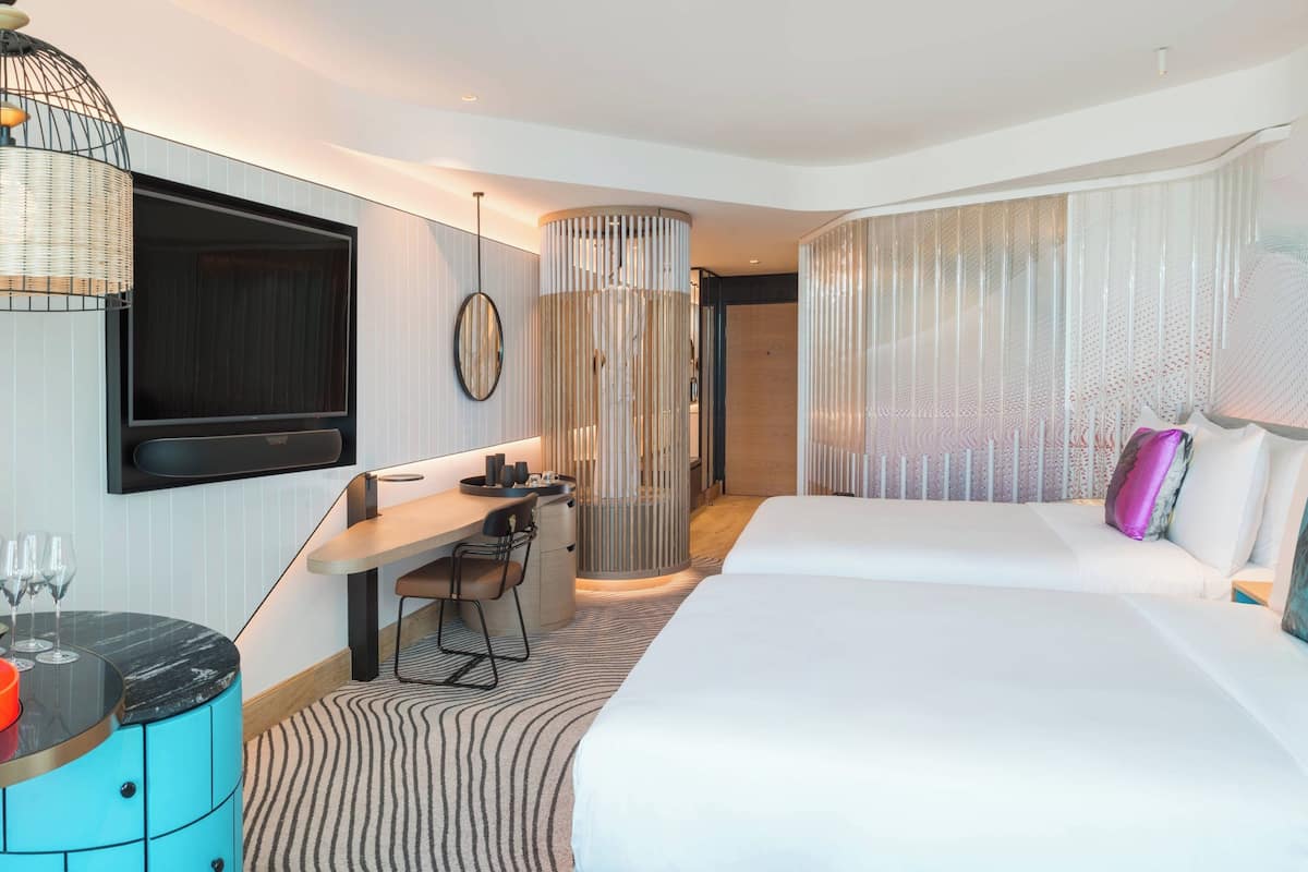 Une chambre d’hôtel moderne dotée d’un grand lit, d’un bureau avec une chaise, d’un téléviseur fixé au mur et d’un pilier décoratif.