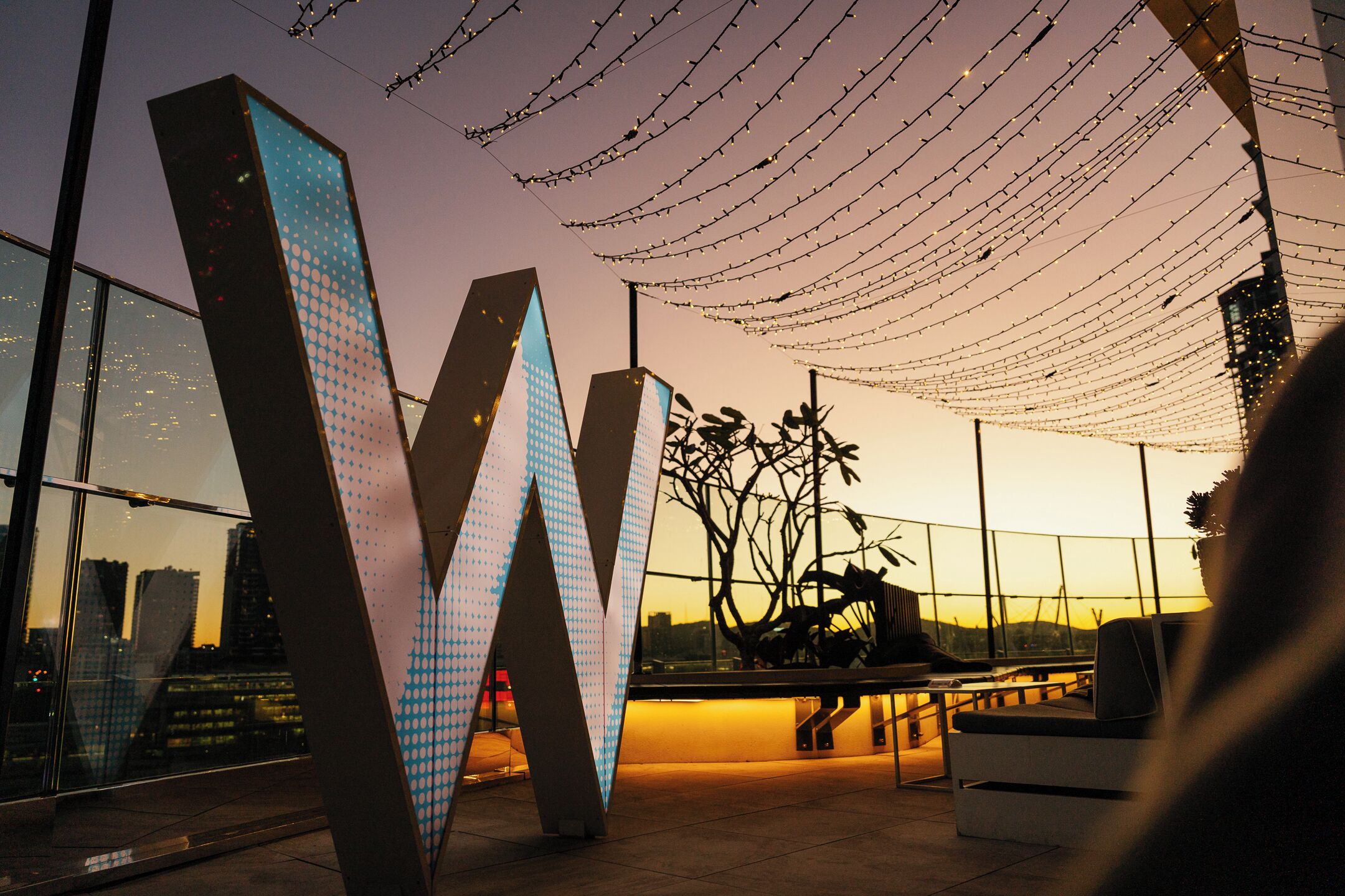 A modern outdoor area with large illuminated letters, seating, and a view of the cityscape.