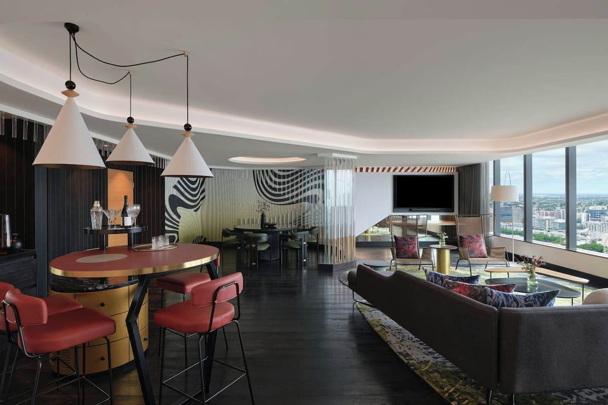 Un hall d’hôtel moderne doté d’un bar, de coins salon et d’un grand écran de télévision.