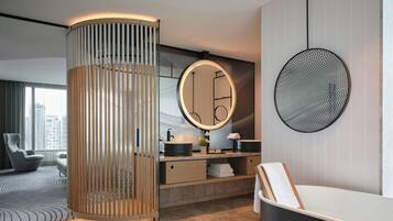 A modern bathroom with a round mirror, a wooden column, and a bathtub.
