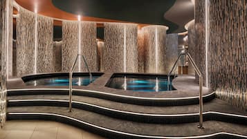 Un área de spa con dos jacuzzis, una escalera curva y una pared con textura.