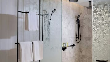 Une salle de bain moderne avec une douche à parois de verre, un porte-serviettes avec deux serviettes et un pommeau de douche.