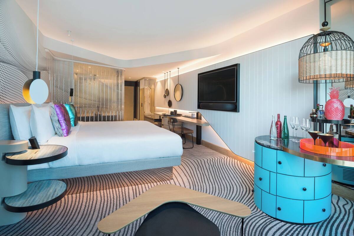 Une chambre d’hôtel moderne équipée d’un grand lit, d’un bureau, d’une télévision et d’un mini-bar.