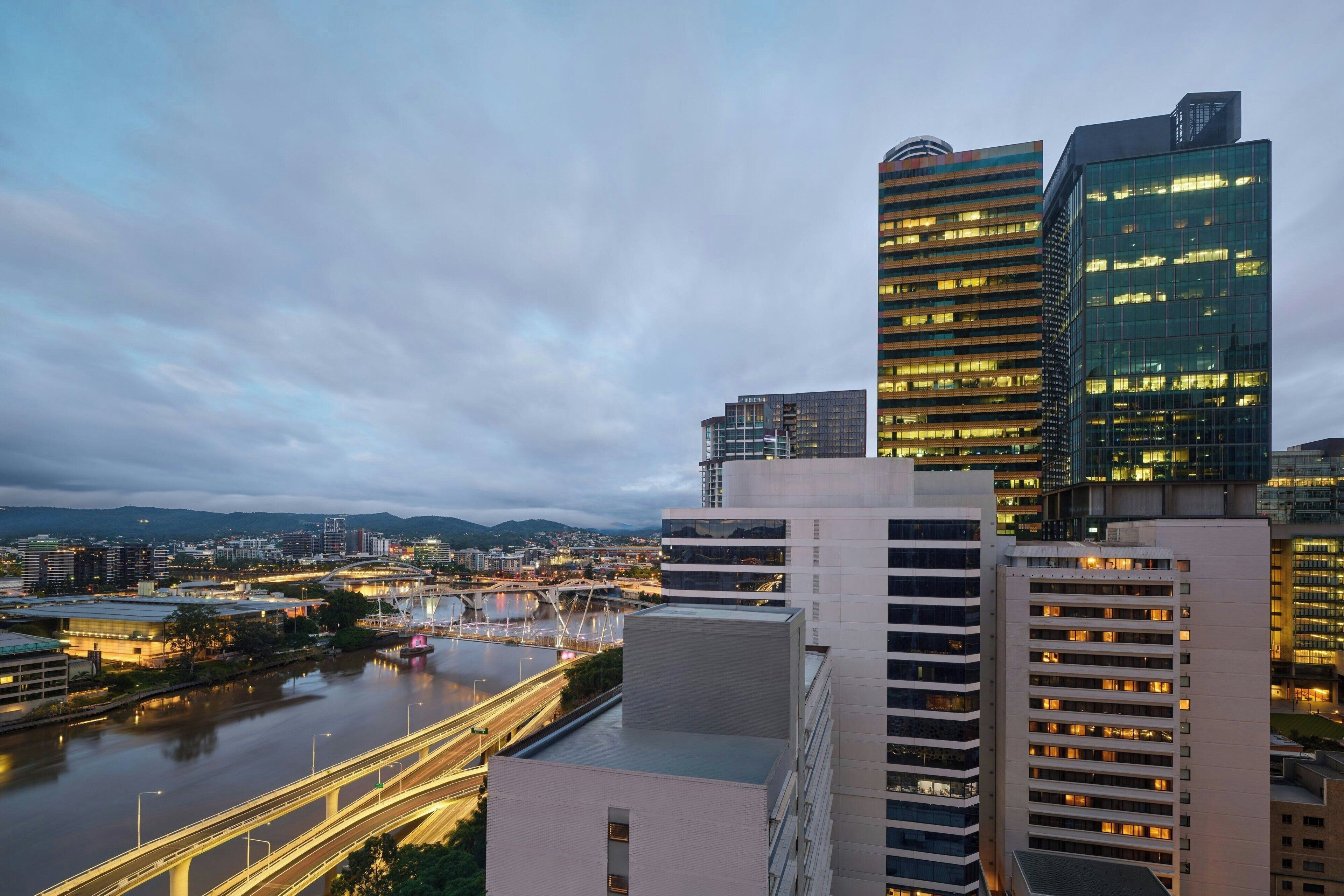 A cityscape with modern buildings, a river, and a bridge.