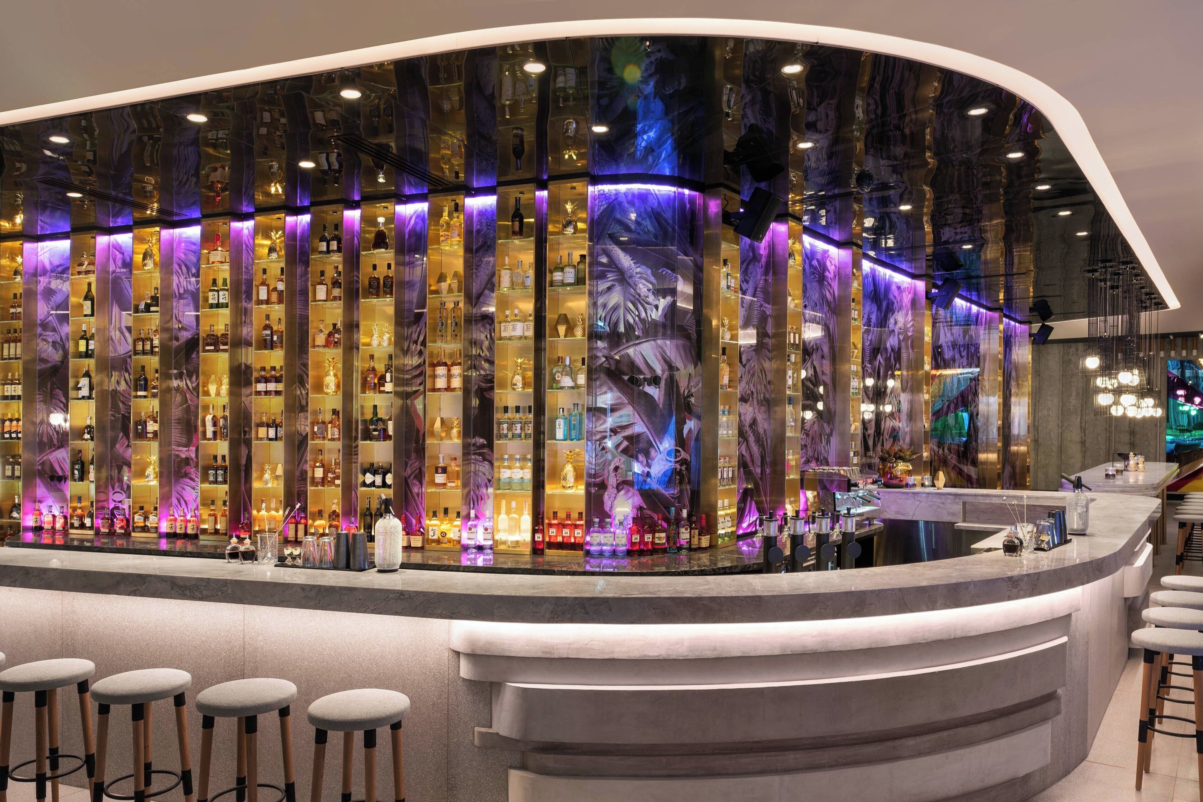 Eine Bar mit einer gebogenen Theke, mehreren Flaschenregalen und Barhocker.