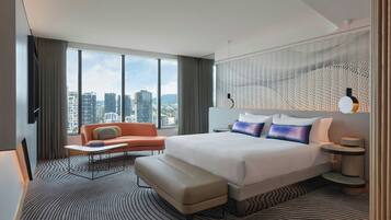 Un hotel moderno con una cama grande, un sofá, una mesita y vistas a la ciudad.