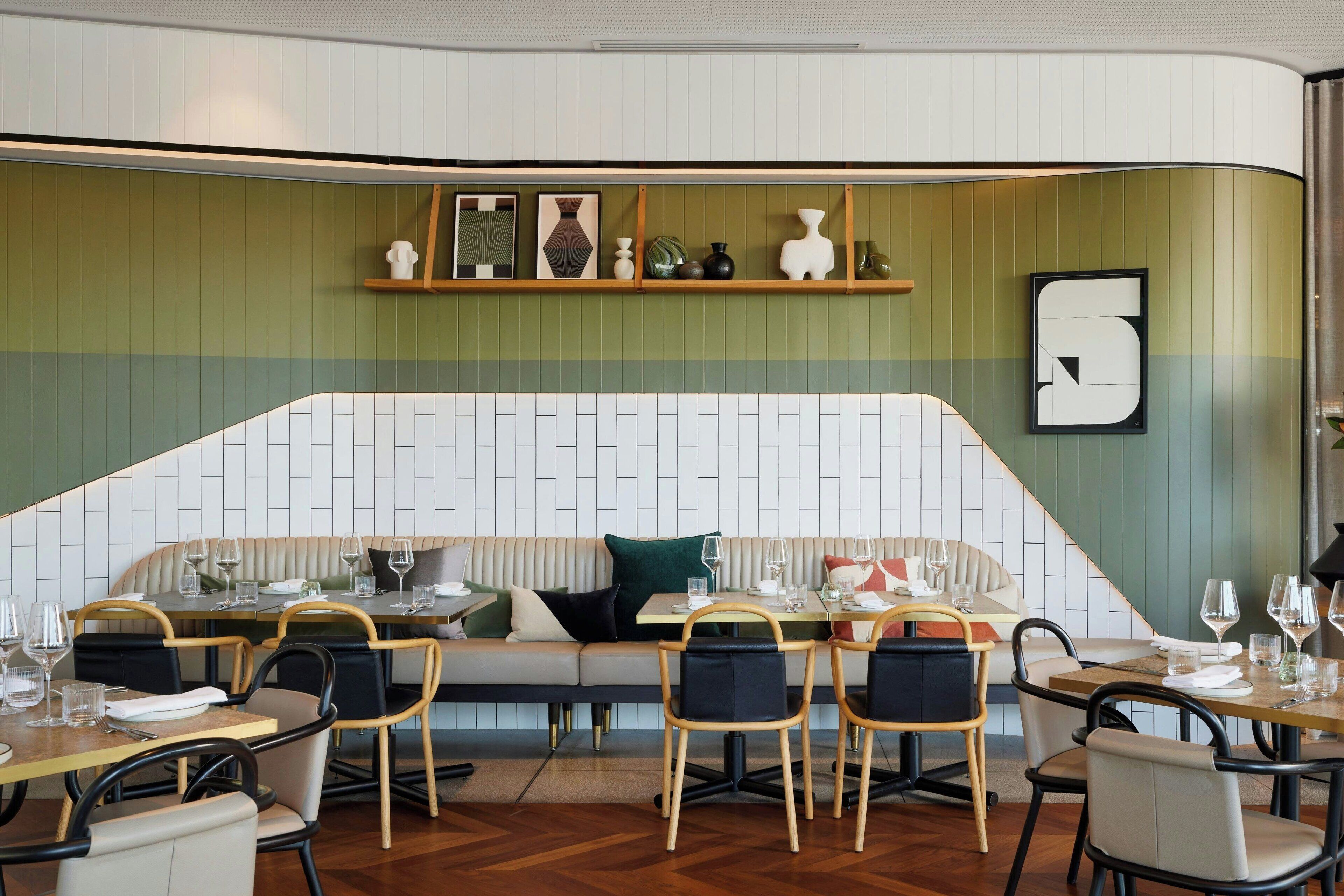 Een restaurant met een groen-wit kleurenschema, houten meubels en diverse decoratieve objecten op planken.