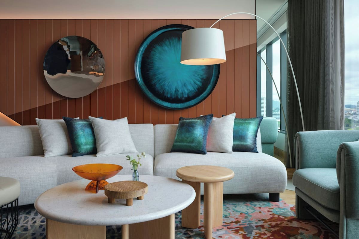 Un salon moderne avec un canapé, deux tables d’appoint et une grande œuvre d’art abstraite accrochée au mur.