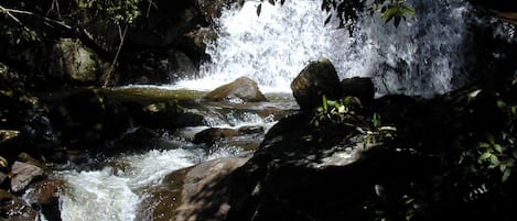 A natural waterfall surrounded by rocks and greenery.
