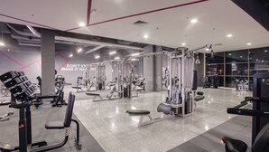 Un gimnasio moderno con diverso equipo de ejercicio, incluyendo máquinas de pesas y bancos.