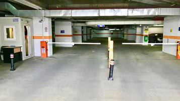 An underground parking garage with concrete floors, metal railings, and orange safety barriers.
