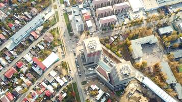 An aerial view of a cityscape with a mix of residential and commercial buildings, roads, and a large parking area.