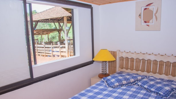 A room with a bed, a window, a lamp, and a wall decoration. - Apto 1 ferias na Fazenda Usina And. Sup. (Bocaina de Minas)