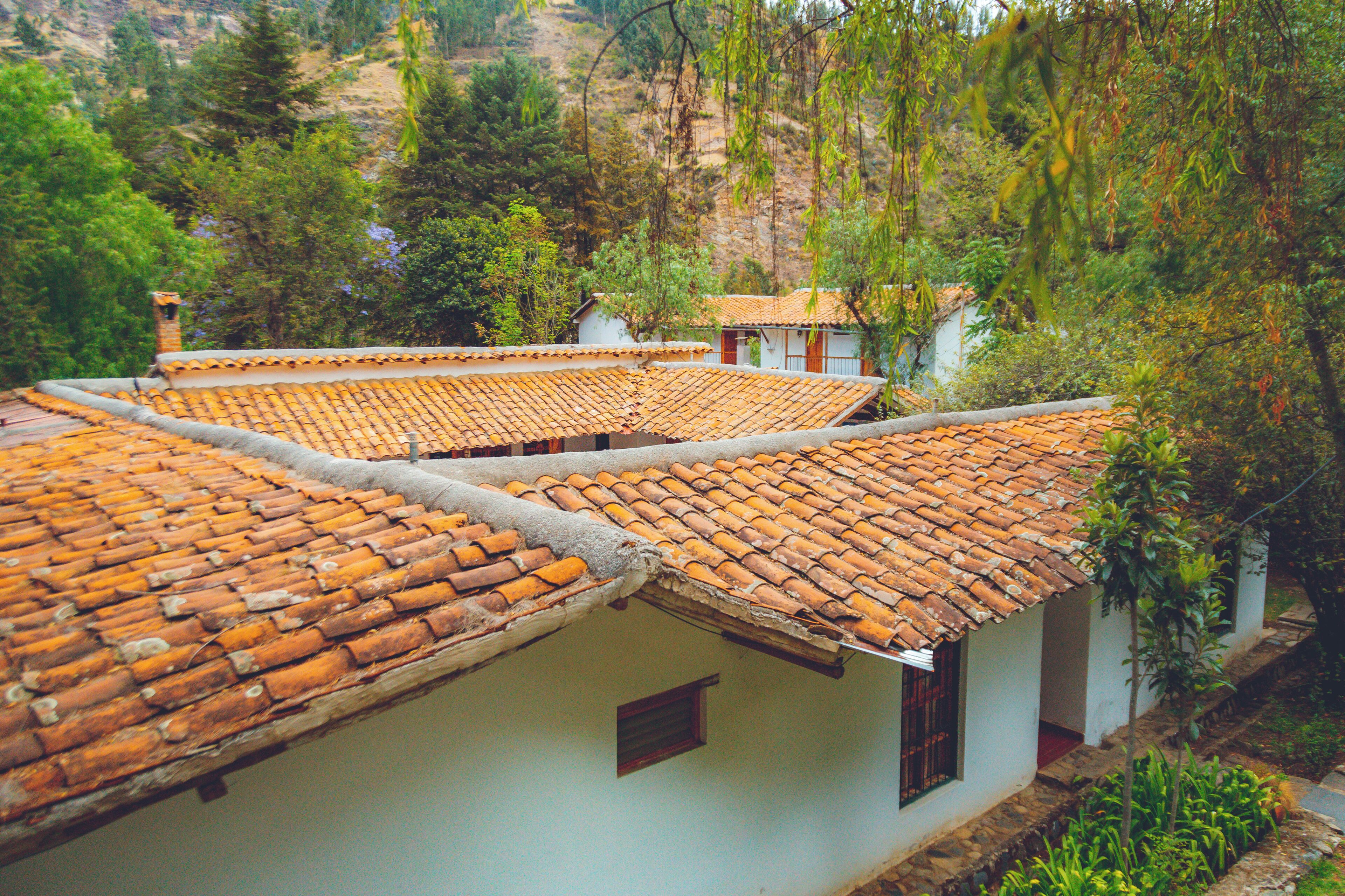 A traditional building with terracotta tiled roofs and white walls, surrounded by lush greenery.