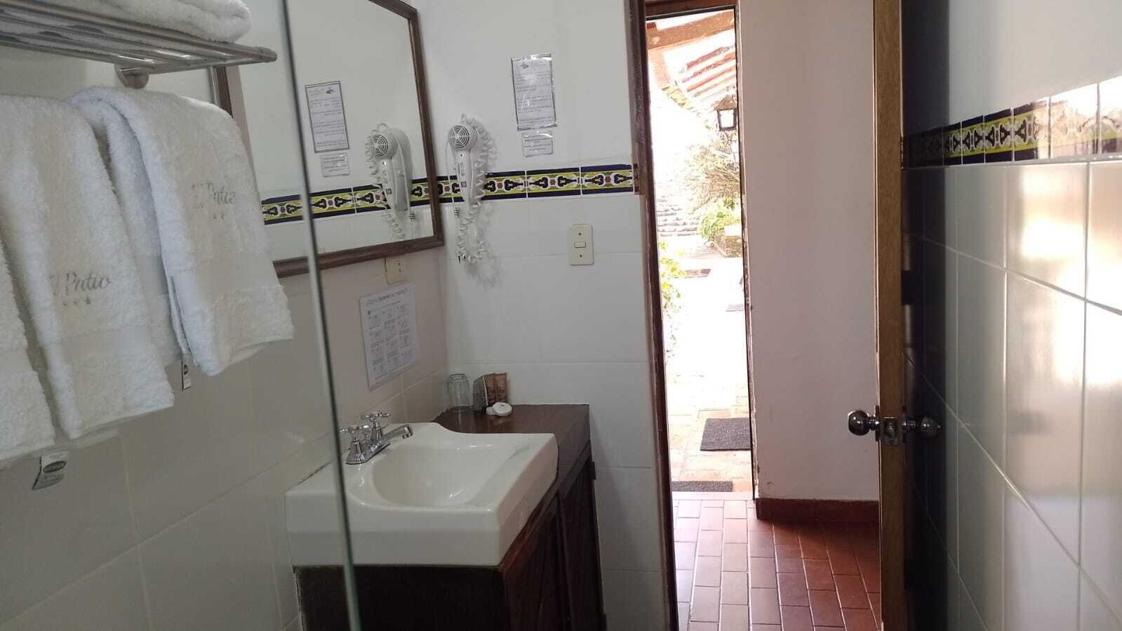 A bathroom with a sink, mirror, and towel rack.