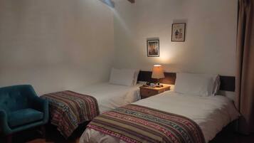 Una habitación con dos camas, una silla, una lámpara y una luz en el techo.