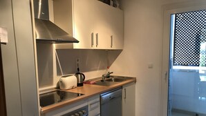 A compact kitchen with a built-in oven, a toaster, and a sink. - Hacienda Riquelme Apartments (Murcia)